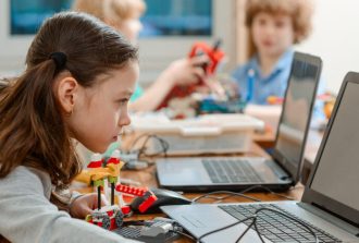 Girl,Using,A,Laptop,While,Assembling,A,Robot,From,Plastic